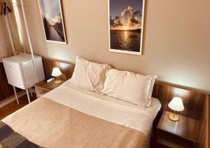 a bedroom with a bed with two lamps and two pictures at Hotel Prudente RP in Ribeirão Preto