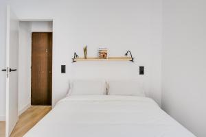 een slaapkamer met een wit bed en een houten deur bij La Casa del Granado in Toledo