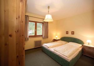 ein Schlafzimmer mit einem grünen Bett mit zwei Tischen und einem Fenster in der Unterkunft Appartementhaus Turracher Höhe in Turracher Hohe