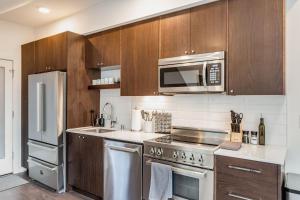 a kitchen with stainless steel appliances and wooden cabinets at Centro house E BY Betterstay in Seattle