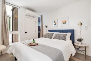 a white bedroom with a blue and white bed and a window at Centro house E BY Betterstay in Seattle