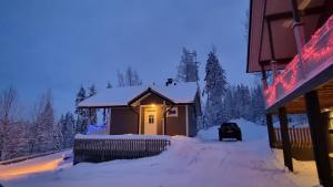 una casa con una luz encendida en la nieve en Villa Magnolia 2 Himos en Jämsä