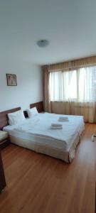 uma grande cama branca num quarto com pisos em madeira em Апартаменты в Belvedere em Bansko