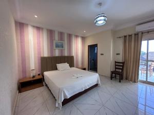 a bedroom with a white bed and a chair at Apartments Plaza Hotel in Kololi