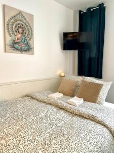 een bed met twee kussens en een schilderij aan de muur bij Studio Cosy Vanves Paris Porte de Versailles in Vanves