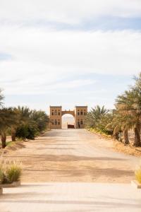 una carretera que conduce a un edificio con palmeras en Sahara pearl Hotel en Merzouga