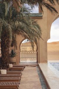 an entrance to a resort with a pool and palm trees at Sahara pearl Hotel in Merzouga