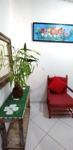 uma cadeira vermelha sentada ao lado de uma mesa com uma planta em Recanto da Vera em Ilhabela