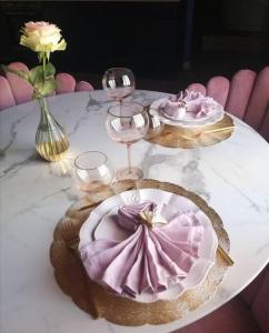 einen Tisch mit einem Teller, Weingläsern und Blumen in der Unterkunft Rose & Blue Spa proche Chalon S/Saône et Beaune in Saint-Martin-en-Bresse