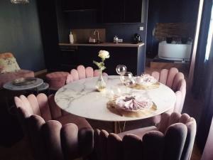 ein Esszimmer mit einem Tisch und rosa Stühlen in der Unterkunft Rose & Blue Spa proche Chalon S/Saône et Beaune in Saint-Martin-en-Bresse