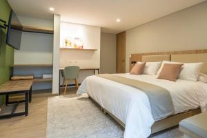 a bedroom with a large bed and a table and a desk at Siete Balcones Hotel y Coworking in Pasto