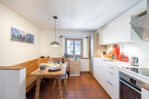 a kitchen with a wooden table and a kitchen with white cabinets at Chasina Bagnera in Scuol