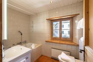 łazienka z wanną, umywalką i oknem w obiekcie Chasina Bagnera w mieście Scuol