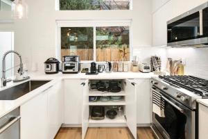 a white kitchen with a sink and a stove at Capitol Luxe Eight BY Betterstay in Seattle