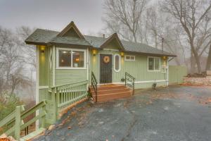 une petite maison verte avec une véranda et une clôture dans l'établissement Mid-Century Mod Cottage, Steps to Lake Gregory!, à Crestline
