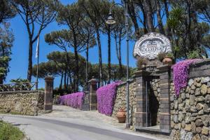 um sinal para a entrada de um parque com flores roxas em Elegant Sorrento Coast Villa with Pool and Tennis Court em Massa Lubrense