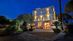 um grande edifício branco com luzes acesas à noite em Elegant Sorrento Coast Villa with Pool and Tennis Court em Massa Lubrense