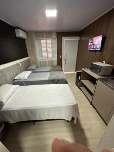 una camera con due letti e una televisione di Loft Lux 5 a Chapecó