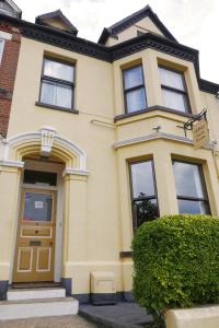 a yellow house with a brown door at Abbey Guest House in Norwich
