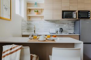 una cocina con encimera con 2 sillas blancas en Orly Suites, en Santiago