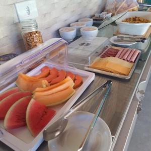 um buffet com frutas em pratos no balcão em Pousada Fenícia em Japaratinga