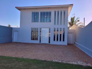a white house with glass doors and a brick driveway at Pousada Recanto Luigi in Brotas