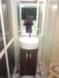 a man taking a picture of a sink in a bathroom at Berkley House in Lagos