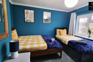 2 camas en una habitación con paredes azules en The Rose Garden - House in the Heart of Basildon by Artisan Stays I Free Parking I Perfect for Contractors or Families, en Basildon