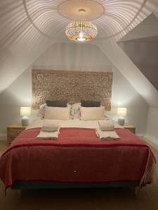 um quarto com uma grande cama vermelha e um lustre em Cottage 7 mins from Henley with gated parking em Henley on Thames