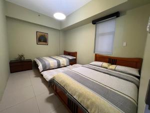 two beds in a room with a window at Miranda 514B 2br at Pico de Loro by Raquel's Place in Nasugbu