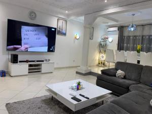 ein Wohnzimmer mit einem Sofa und einem Flachbild-TV in der Unterkunft Villa Palmeraie in Brazzaville