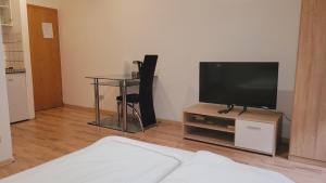 a living room with a television and a table with a chair at Saarbrücken City Apartments in Saarbrücken