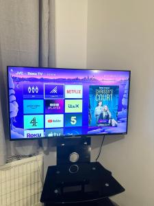 a flat screen tv sitting on top of a black stand at 3 Bedroom fully equipped house with garden in Manchester