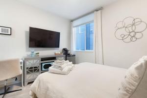 a white bedroom with a bed and a television at The Canal 15A BY Betterstay in Seattle