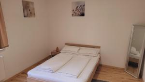 ein weißes Bett in einem Zimmer mit Spiegel in der Unterkunft Saarbrücken City Apartments in Saarbrücken