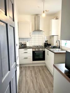 a kitchen with white cabinets and a wooden floor at 3 Bedroom fully equipped house with garden in Manchester