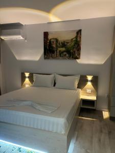 1 dormitorio con 1 cama blanca y una pintura en la pared en CELINE CONFORT N. D. COCEA en Bucarest