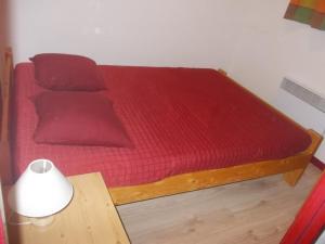 a bed with red sheets and a table with a lamp at Appartement Valfréjus, 2 pièces, 6 personnes - FR-1-265-193 in Valfréjus