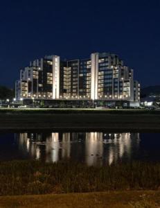 a large building at night with its reflection in the water at My River Walk apartment - Ilidza in Sarajevo