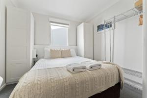 a white bedroom with a bed with towels on it at Horizons 216 - Deluxe Lake Front Studio l Pool l Tennis l Air-Con in Jindabyne +10 photos