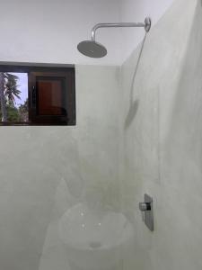 a shower in a white bathroom with a window at CosyBe Villas in Inhambane