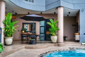 een patio met een tafel met een parasol en een zwembad bij Hotel Osvé Boutique Cali in Cali