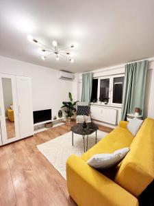 uma sala de estar com um sofá amarelo e uma mesa em Lola’s apartament close to city center em Bucareste