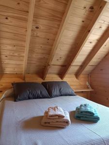 2 toallas en una cama en una habitación con techos de madera en Cabañas Le Parc en Delta de Tigre en Tigre