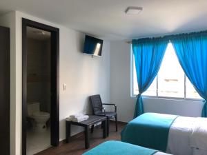 una camera d'albergo con un letto, una sedia e una finestra di First Class Hotel en Baños - Ciudad Volcan a Baños