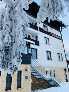 a building with snow on the branches of a tree at Pensiunea Panoramic in Vartop