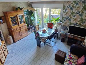 a living room with a table and a tv at La Villa Bleue in Beauchastel