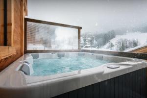 a jacuzzi tub in a snowy room with a window at Chalet Trusquin - OVO Network in Le Grand-Bornand