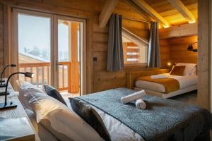 a bedroom with two beds in a log cabin at Chalet Trusquin - OVO Network in Le Grand-Bornand