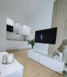 sala de estar blanca con TV de pantalla plana en la pared en Apartamentos Franchy C derecho, en Telde